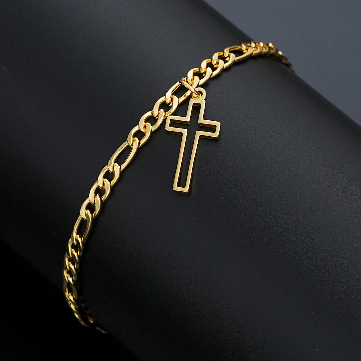 Close-up of the hollow cross charm on La Cruz gold Figaro bracelet