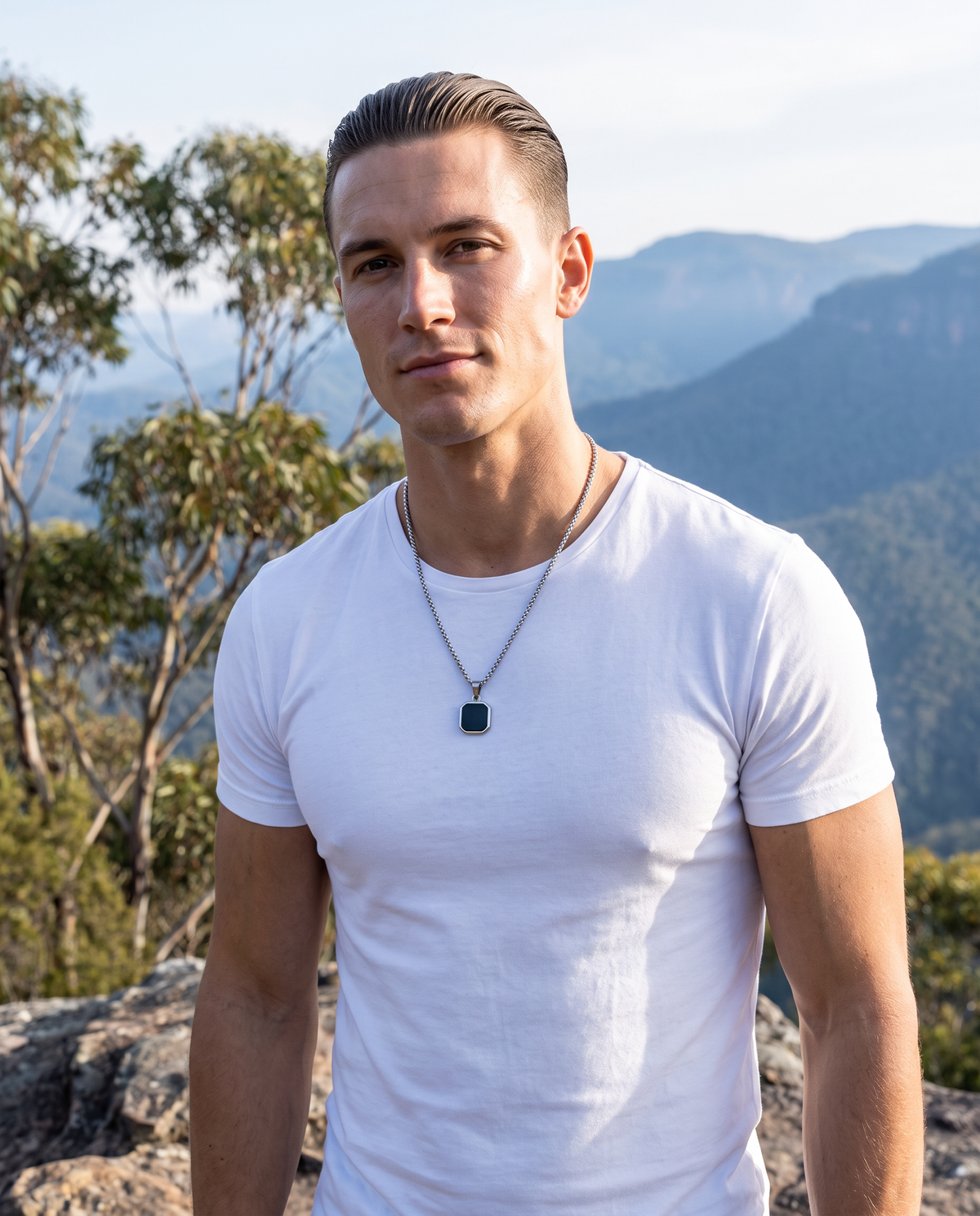 Man in a white t-shirt at a mountain lookout wearing El Bloque silver black square pendant on a silver box chain