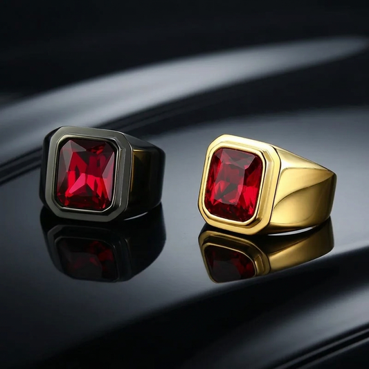 Gunmetal and gold red-stone rings on polished black metal